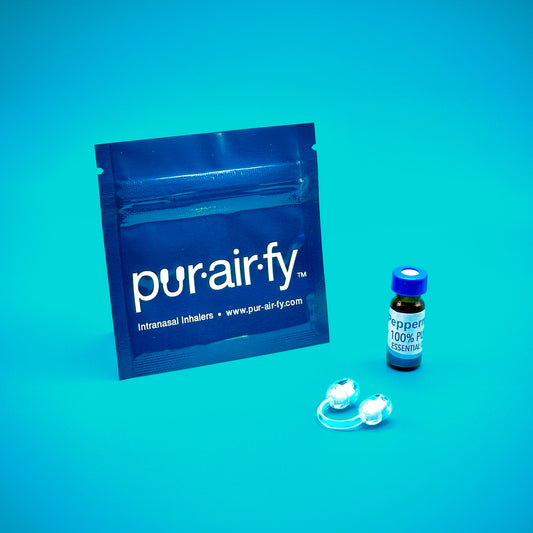 A Pur-Air-Fy intranasal inhaler set, including a resealable blue pouch, a small bottle of essential oil labeled "Orange 100% Pure Essential Oil," and a clear nasal inhaler, placed against a blue background